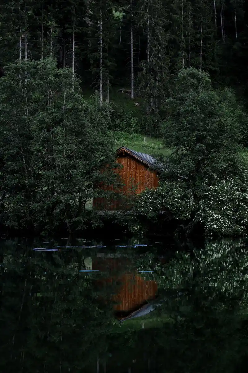 Holzhaus an einem stillen Waldsee mit Spiegelung